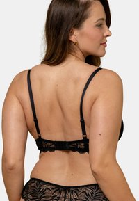 Soutien-gorge en dentelle noire avec bretelles ajustables, fermeture à crochets et œillets, et un motif floral le long de la bande et des bonnets.