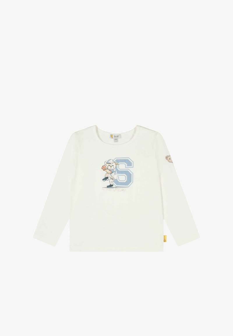 Bílé tričko s dlouhým rukávem, na přední straně s modrou grafikou "S" a ilustrací medvěda hrajícího fotbal, se malou nášivkou medvěda na rukávu.