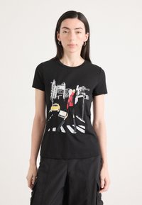 Must musta t-särk, millel on graafiline illustreerimine tänava stseenist, kus on kollane takso, modelleeritud pika juustega inimese poolt.