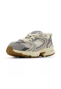 Harmaa ja kerma valkoinen juoksukenkä, jossa on verkkopäällinen ja mokkanahkaiset yksityiskohdat. Kenkässä on kuvioitu ulkopohja ja nauhat. Brändäys näkyy sivussa ja kielen kohdalla.