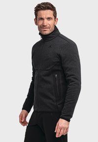 Schwarze Softshelljacke mit Reißverschluss vorne, hohem Kragen und zwei Seitentaschen. Mit strukturiertem Stoff und kontrastierenden schwarzen Akzenten.