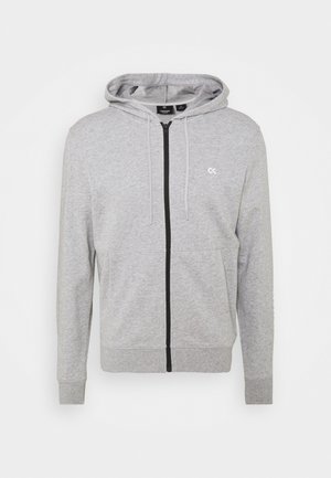 Gray zip-up hoodie made of soft material, featuring a front zipper, drawstring hood, and subtle logo on the chest. Standard fit.