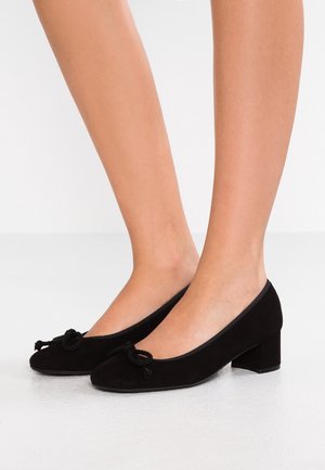 Czarne zamszowe buty na szerokim obcasie, z zaokrąglonym noskiem i ozdobnym detalem w postaci węzła z liny na przodzie. Miękka tekstura i prosty kształt.