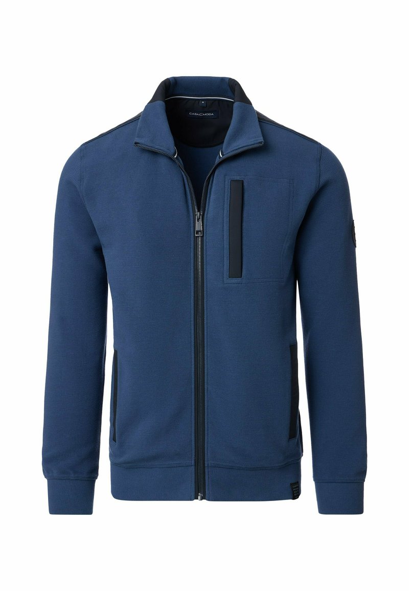 Marineblauwe ritsjack met een gestructureerde stof, zwarte accenten, een zijzak en een hoge kraagontwerp. Voorzien van ribgebreide manchetten en zoom.