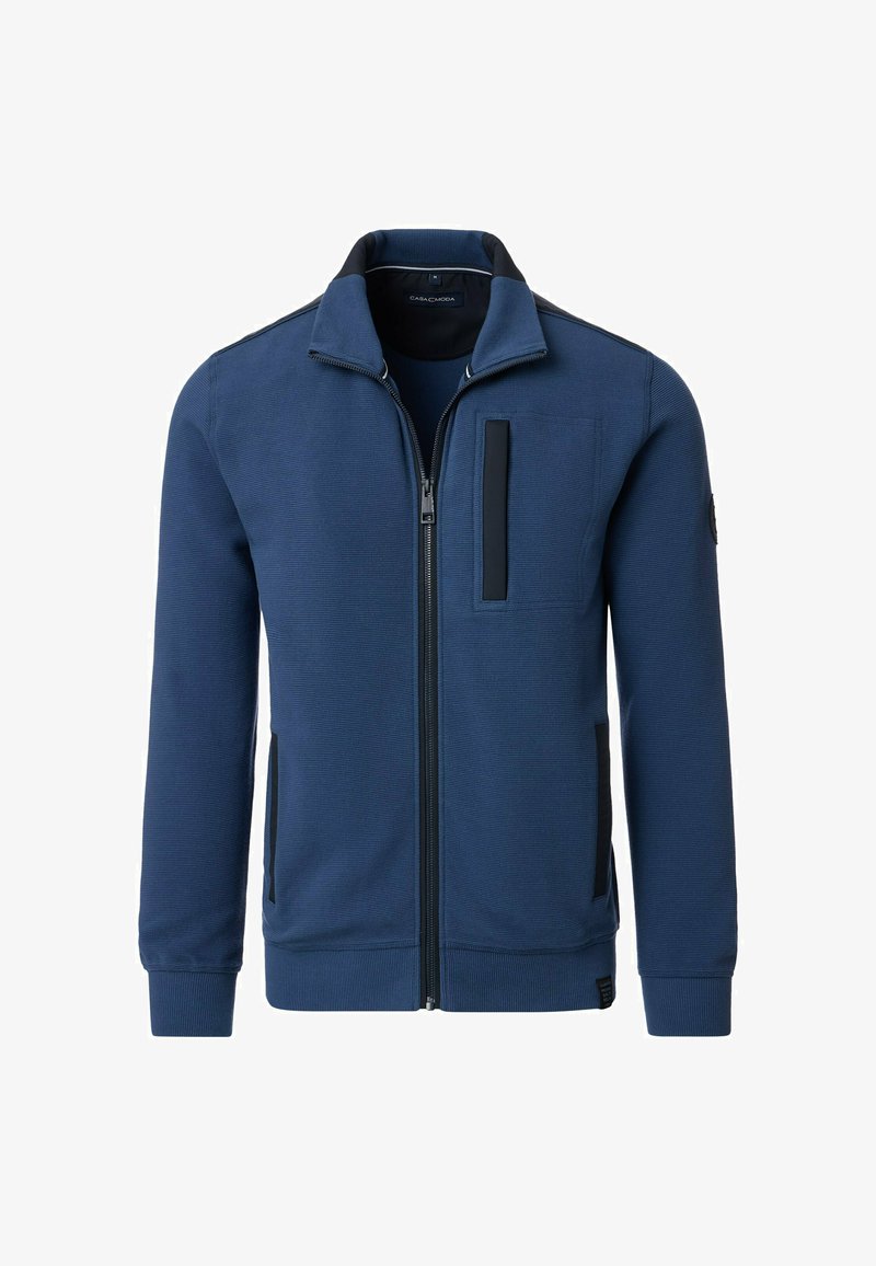 Marineblauwe ritsjack met een gestructureerde stof, zwarte accenten, een zijzak en een hoge kraagontwerp. Voorzien van ribgebreide manchetten en zoom.