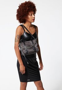 Grijze schoudertas met een gestructureerde afwerking, voorzien van een zilveren kettinkje en zwarte accenten. Compacte rechthoekige vorm met verstelbare bandjes.