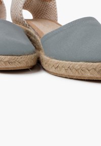Šedé plátěné espadrilky s jutu rope podešví, jemně tkaným popruhem a plochým designem, které představují jednoduchý, neformální vzhled.
