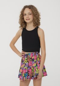 Top cropped nero abbinato a una skort colorata con motivo floreale che presenta colori vivaci come rosa, viola e verde su uno sfondo nero.