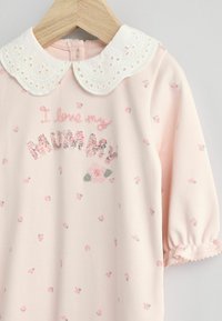 Helles rosafarbenes Baumwilderkleid mit einem weißen bestickten Kragen, verziert mit Blumenmustern und dem Text "Ich liebe meine MUMMY" in bunten Fäden.