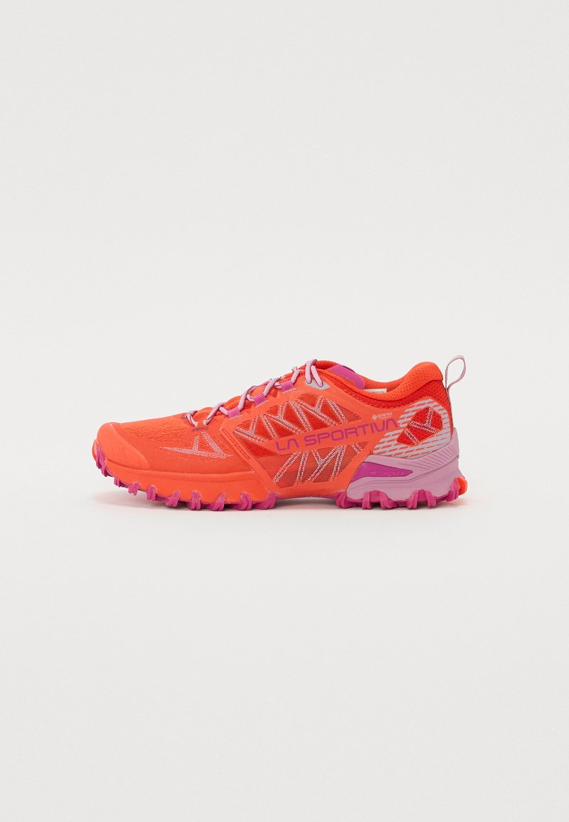 Shoe de corrida trail laranja luminoso com um upper em malha respirável, detalhes em rosa, sola robusta e texturas nos lados.