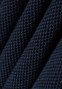 Dunkelblauer strukturierter Strickstoff mit einem weichen, erhabenen Muster, das eine glatte Oberfläche und sichtbare Stiche aufweist, die einen dreidimensionalen Effekt erzeugen.