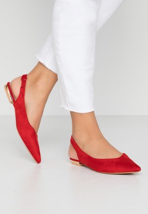 Rode suède slingback ballerina's met een spitse neus, een gestructureerde afwerking en een kleine metalen accent aan de achterkant. G gedragen met witte cropped broeken.