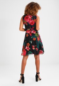 Sukienka z haftem kwiatowym, prezentująca czarną bazę, jasnoróżowe i zielone wzory kwiatowe, bez rękawów oraz rozkloszowany dół z zamkiem błyskawicznym z tyłu.