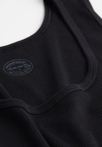 Schwarzes geripptes Tanktop mit rundem Ausschnitt und glatten Nähten. Es hat ein kleines Logo-Tag in der Mitte des Stoffes.