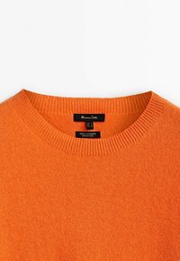 Pull ras du cou orange vif en 100 % cachemire, avec col côtelé et étiquettes de produit à l'intérieur du col.