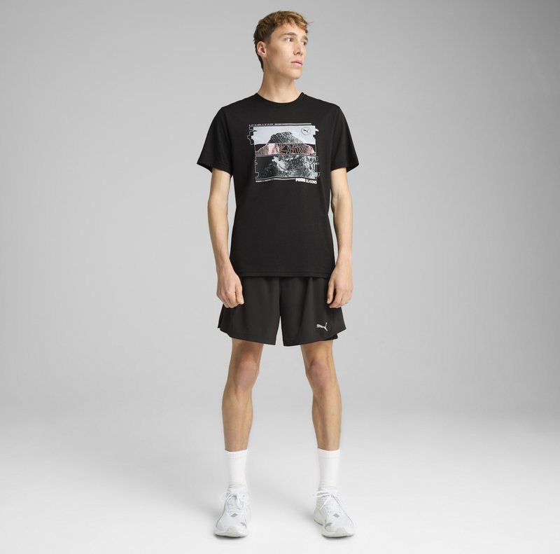 Sort bomulds t-shirt med grafisk print, parret med sorte shorts og hvide ankelstrømper. Skoene er grå med diskrete designaccenter.