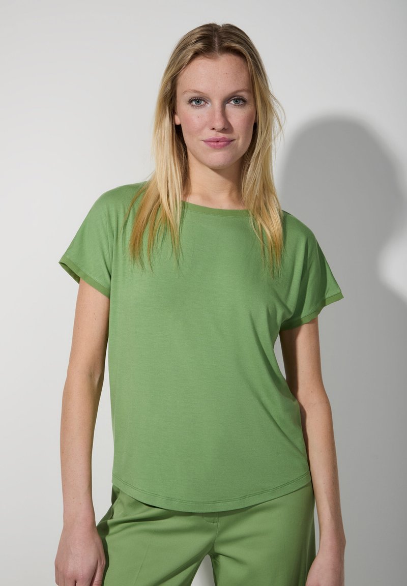 Kurzarm-T-Shirt mit Rundhalsausschnitt aus hellgrünem Stoff. Weiche Textur mit lockerer Passform, kombiniert mit passenden grünen Hosen.