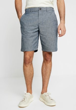 Herregrå chambray-shorts med moderat pasform, enkelt knaplukning og sidelommer. Bæres med lyse sneakers.