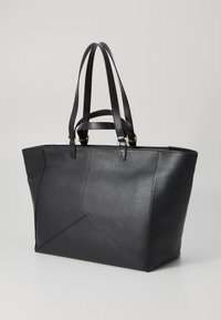 Sac fourre-tout en cuir noir avec une finition texturée, doté de poignées allongées et d'un design géométrique sur le panneau avant. Accents en métal doré.
