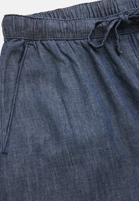 Denim-joggers med elastisk midjeband, snörning och sidofickor, i en djupblå färg med en mjuk, texturerad yta.