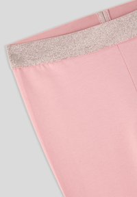 Różowe legginsy o gładkiej fakturze i błyszczącej, brokatowej talii. Charakteryzują się dopasowanym krojem oraz prostą, czystą formą.