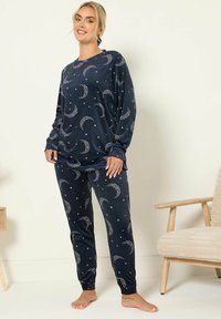 Pigiama blu navy realizzato in tessuto morbido, con un motivo a luna crescente e stelle. Maniche lunghe e polsini elasticizzati sui pantaloni.