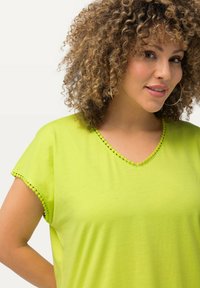 Top verde brillante de cuello en V con mangas cortas, que presenta un borde texturizado a lo largo del escote y las mangas. Tela suave con un corte relajado.