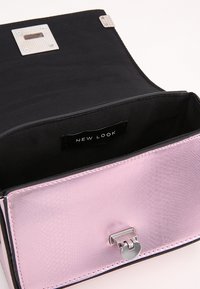 Borsa a tracolla in ecopelle rosa con finitura testurizzata, fodera in tessuto nero e dettagli in metallo argentato. Presenta una chiusura a ribalta e un'etichetta del marchio all'interno.