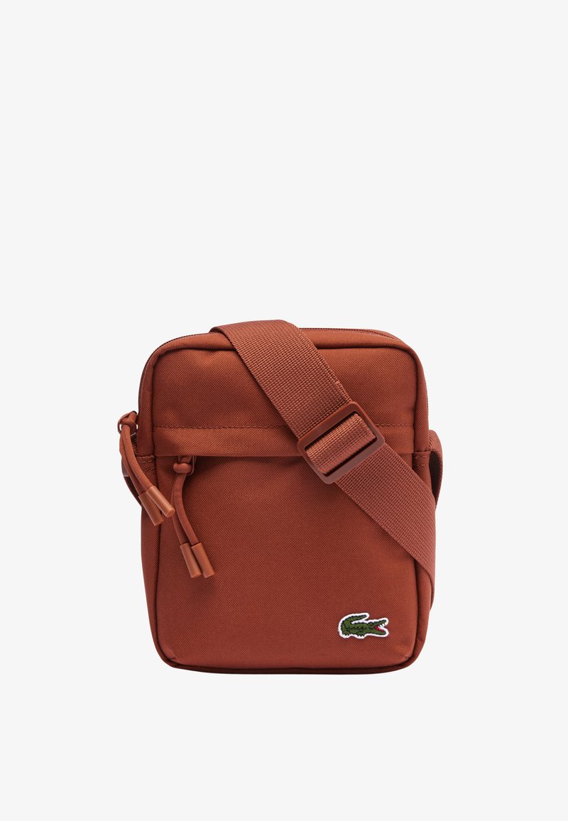 Geantă de umăr roșie din nailon, cu formă rectangulară, curea ajustabilă, închidere cu fermoar și detaliu distinctiv cu logo-ul Lacoste.