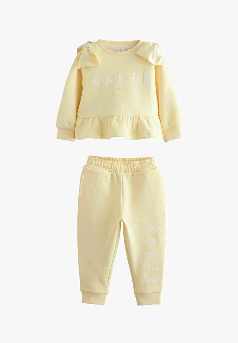 Gelbes Sweatshirt- und Hosen-Set. Das Sweatshirt hat einen gerüschten Saum, Logotext und Schleifenakzente. Die Hose hat einen elastischen Bund und ein Logodetail.