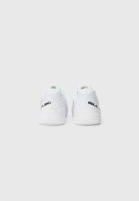 White athletic shoes with a smooth texture, featuring a contrasting black logo, padded collar, and rubber outsole designed for grip.