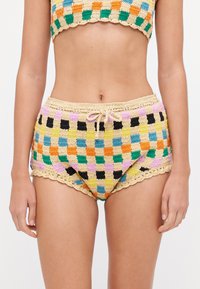 Bas de bikini au crochet avec un motif checkerboard coloré en vert, bleu, orange, jaune et noir. Comprend un bord en dentelle festonné et un cordon de serrage.