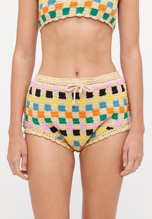 Parte inferior de bikini de ganchillo con un colorido patrón de tablero de ajedrez en verde, azul, naranja, amarillo y negro. Presenta un borde de encaje con forma de concha y cordón ajustable.