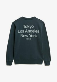 Sudadera de color verde oscuro con gran texto blanco en la parte posterior: "Tokio Los Ángeles Nueva York". Puños y dobladillo acanalados, textura de tela suave.