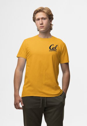 Žluté bavlněné tričko s námořnickým logem s nápisy "Cal" a "University of California." Kulatý výstřih, krátké rukávy a volný střih.
