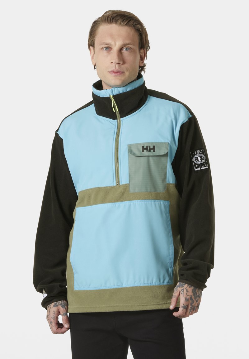 Chaqueta tipo pullover con paneles en azul claro, negro y verde olivo, cierre con cremallera, cuello alto y un bolsillo en el pecho con detalle de logo.