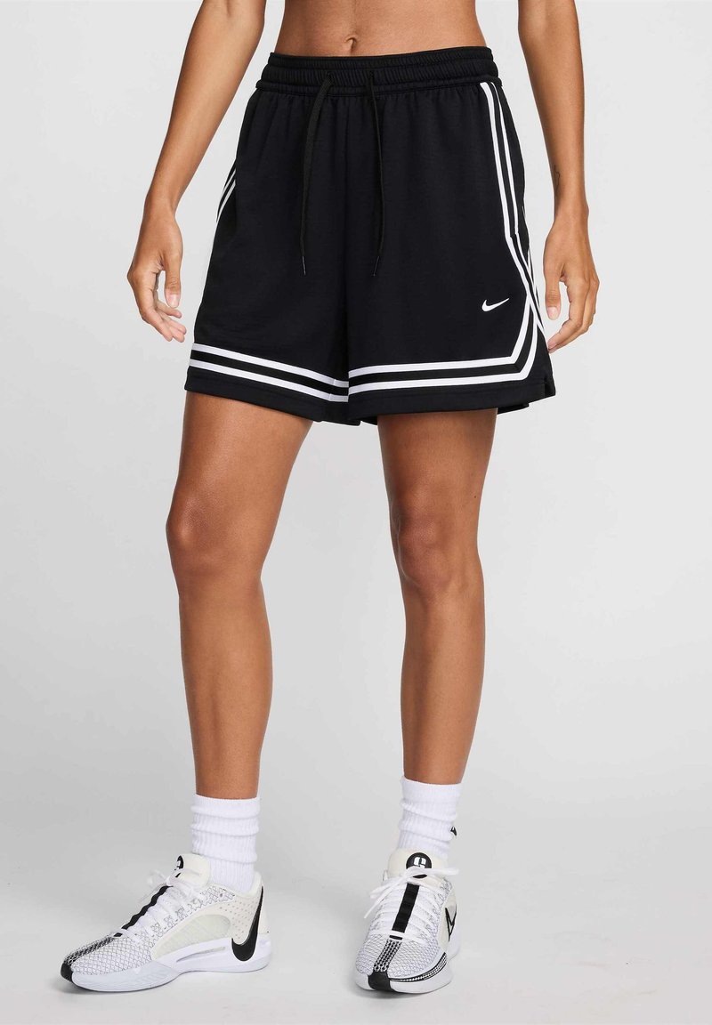 Black athletic shorts with white stripes, an elastic waistband, and a drawstring feature. Paired with white and black sneakers and socks.