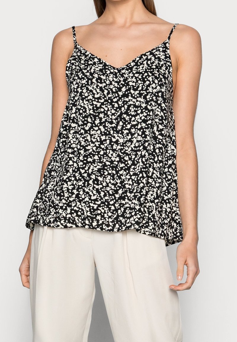 Top senza maniche nero con scollatura a V, caratterizzato da un motivo floreale bianco, silhouette fluida e spalline sottili regolabili.