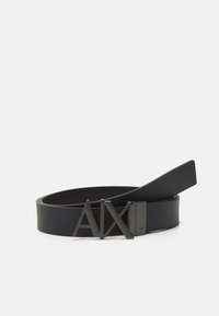 Black leather belt featuring a matte black buckle with "AX" logo. Smooth texture and adjustable design with a sleek, modern silhouette.