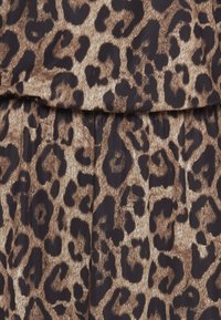 Látka s leopardím vzorem v odstínech hnědé a černé, se hladkým povrchem s jemným leskem a volnými záhyby na švu.