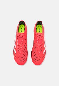 Bright red athletic shoes feature a sleek design with a textured surface and contrasting white accents. Includes black inner lining and laces.