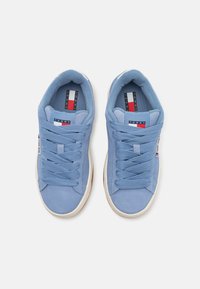 Baskets en suede bleu clair avec des lacets texturés, des doublures rembourrées et une semelle en caoutchouc blanche. Logo sur la languette et sur le côté.
