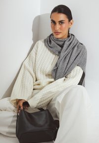 Cream cable-knit sweater, gray scarf, and cream wide-leg pants. Black leather handbag. Smooth textures and neutral color palette. Minimalist design.