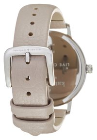 Correa de reloj de cuero beige claro con hebilla plateada; caja redonda con un dial sencillo; posicionada en un ángulo para enfatizar los detalles de la hebilla.