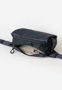 Donkerblauw schoudertasje met een ritscompartiment, voorzien van een textuurstof, binnenzak en een verstelbare schouderband.