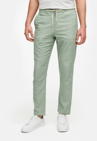 Ljusgröna lätta byxor med elastisk midja och dragsko. Raka passform med subtil textur. Matchas med vita sneakers.