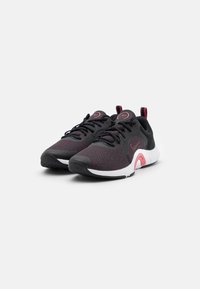 Scarpe sportive nere e rosse con tomaia in mesh, design texturizzato, suola bianca e dettagli rosa sul tallone e sul logo.