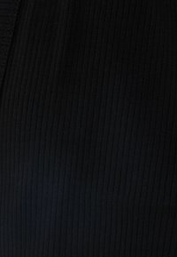 Tissu côtelé noir avec une surface texturée, présentant des lignes verticales et une finition lisse, adapté à diverses conceptions de vêtements.