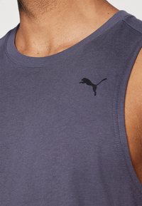 Débardeur sans manches bleu marine, fabriqué en tissu doux, avec un logo Puma noir sur le côté gauche de la poitrine et un col arrondi.