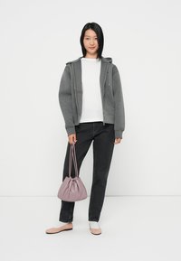 Pilkos zip-up gobtuvės virš baltos marškinėlių, derinamos su juodomis kelnėmis ir šviesiai rožiniais bateliais. Lavandinė raišteliais užsegama kuprinė puikiai užbaigia aprangą.